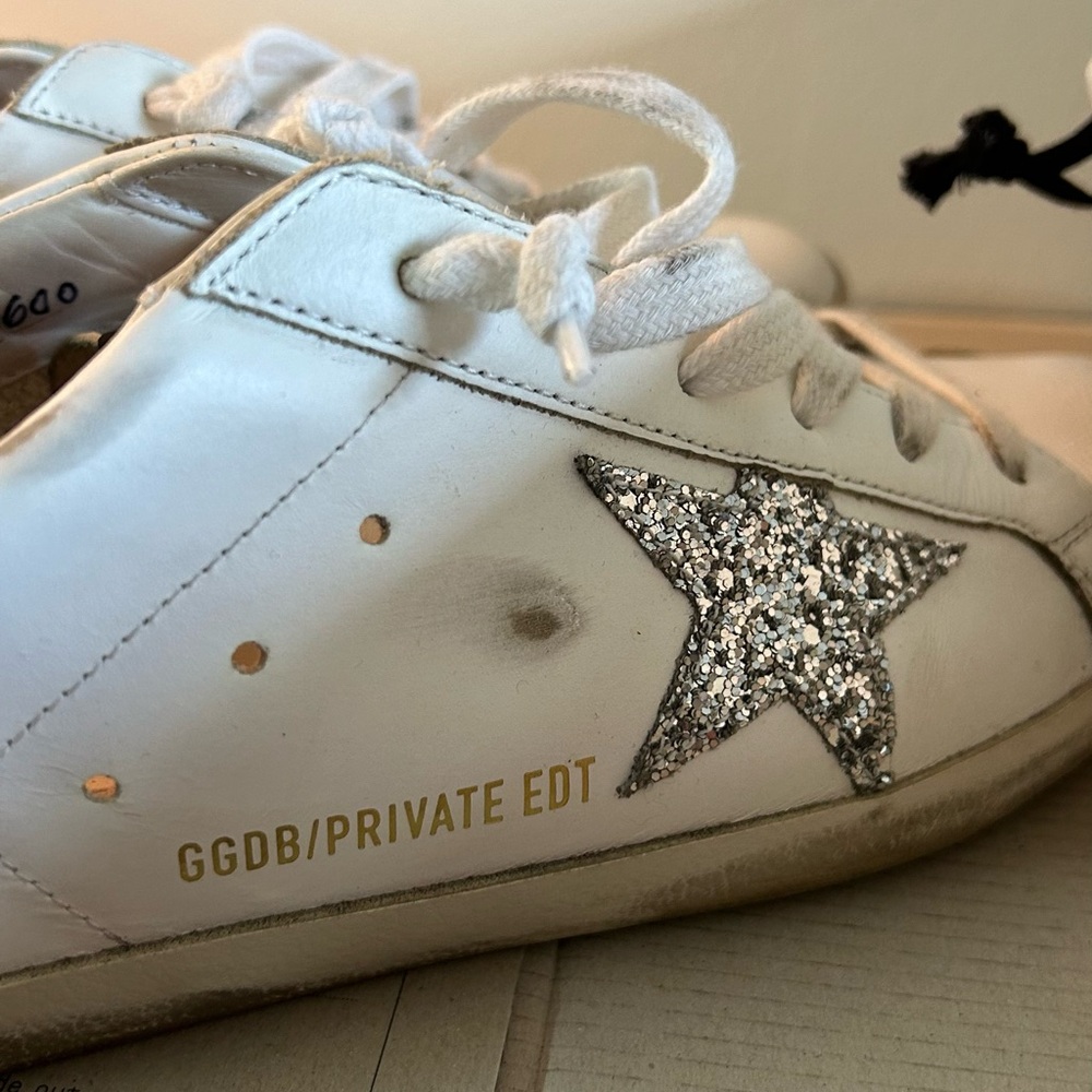 Golden Goose Super Star white sneakers with silver glitter star.